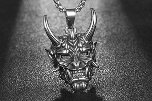 Gros plan du pendentif masque Hannya en argent avec chaîne box sur fond gris