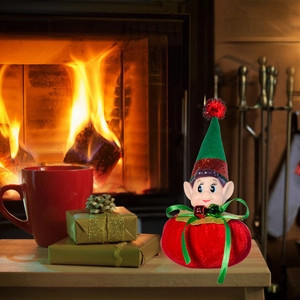 Christmas elf doll on a festive table with red gifts and a cozy fireplace background