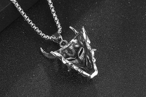 Gros plan détaillé d'un pendentif masque de démon sculpté en acier inoxydable noir oxydé
