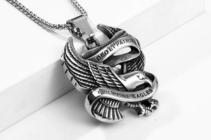 Detailed macro view of vintage stainless steel eagle pendant with engraved Latin mottos