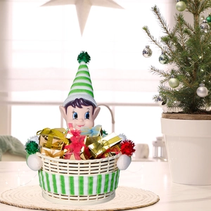 Nahaufnahme von Weihnachtself-Süßigkeitenkorb mit goldenen Geschenken auf festlichem Tisch