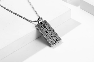 Dettaglio macro del ciondolo militare con incisione Kanji e trama rock vintage