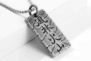 Dettaglio macro del ciondolo militare vintage in acciaio inox con scritte Kanji incise