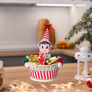 Detailansicht eines Weihnachts-Elfen-Korbs gefüllt mit goldenen Geschenkboxen auf einem Holztisch