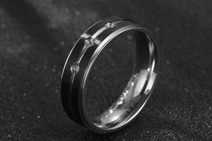 Macro shot of silver stainless steel band featuring 3 inset zircons on a dark background