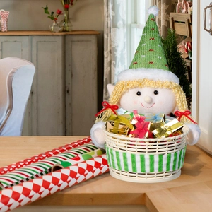 Detail of Christmas elf doll holding a woven basket with colorful gift boxes on wood table