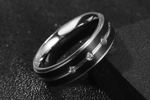 Macro shot of black matte ring with silver inlay and three sparkling diamonds