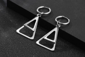 Vue macro de boucles d'oreilles créoles en acier argenté avec breloques triangulaires