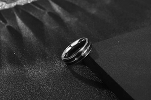 Macro shot of dark grey stainless steel ring with subtle center line and small crystals