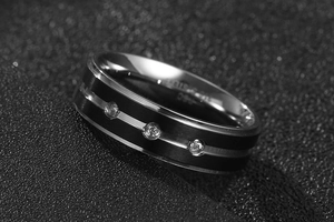 Macro shot of black tungsten steel ring with silver accents and triple crystal inlay