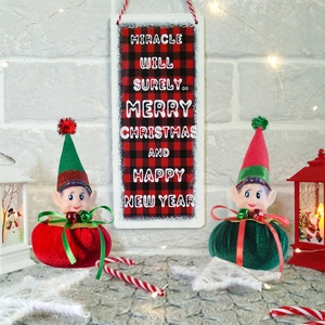 Close-up of red and green Christmas elf ornaments with velvet bodies and festive bells