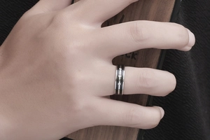 Detail of a two-tone stainless steel ring featuring three embedded clear zircon stones