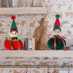 Detailed plush Christmas elves with bells and bows on a wooden shelf for home decor