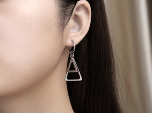 Détail de boucles d'oreilles en acier argenté à triangles superposés sur un mannequin