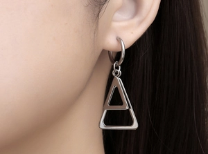 Gros plan de boucles d'oreilles minimalistes en acier à double triangle sur l'oreille