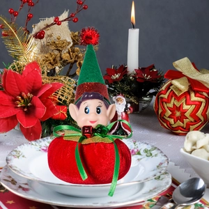 Close-up of a Christmas elf ornament on a festive dining plate with holiday decorations
