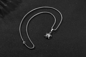Macro detail of the stainless steel sea turtle pendant and round bead chain texture
