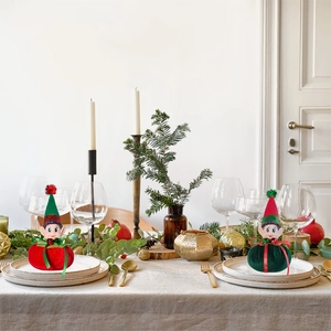 Christmas elf plush dolls in red and green set on a festive dining table setting