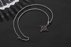 Vue détaillée du collier en acier titane avec pierre de zircon rouge et pendentif croix