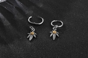 Detail of silver eagle feather charms on round hoop earrings with golden peace symbols