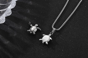 Macro shot of vintage silver turtle pendants and chain on a textured dark background