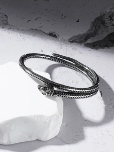 Détail macro du bracelet serpent argenté avec écailles et yeux en pierres rouges