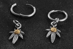 Macro detail of retro silver eagle feather leaf earrings with golden center relief