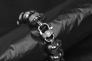 Makroaufnahme von Punk-Totenkopf-Armband aus Edelstahl mit Kreuzschließe auf Leder