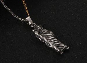 Macro shot of bicolour gold and silver chain with detailed religious saint pendant