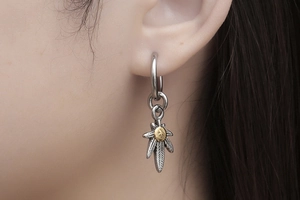 Close-up of punk style leaf pendant earring in retro silver finish on a male model