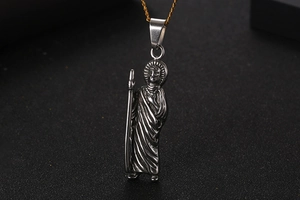 Detailed macro view of vintage silver Saint pendant with aged metal texture and engraving