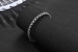 Macro shot of silver wheat chain bracelet in stainless steel on black display stand