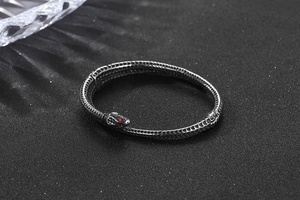 Gros plan sur un bracelet serpent noir vintage avec écailles et yeux en pierre rouge