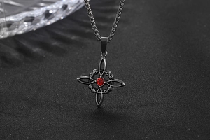 Vue macro du collier étoile en acier titane avec cristal rouge sur fond noir mat