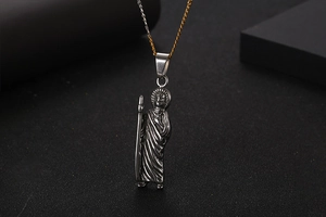 Close-up of vintage Saint Jude relief pendant on a textured stainless steel chain