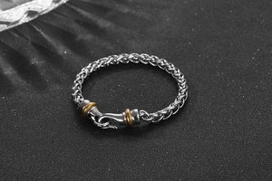 Detail of hip-hop men's braided titanium steel bracelet with gold-plated ring accents