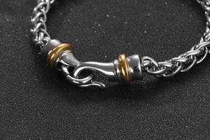 Macro detail of bicolored silver and gold stainless steel braided chain bracelet with hook clasp