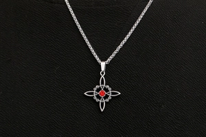Détail macro du collier en acier titane argenté avec pierre rouge et pendentif