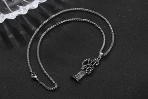 Détail macro du pendentif Santa Muerte en acier titane vintage avec chaîne tressée