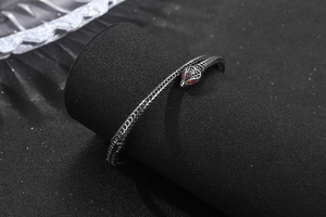 Détail d'un bracelet serpent vintage avec yeux en pierres rouges et texture d'écailles
