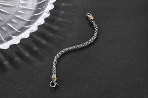 Detailed close-up of wheat chain bracelet with gold accents and lobster clasp
