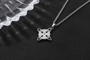 Gros plan du pendentif croix celtique en acier inoxydable argenté sur fond noir texturé
