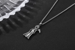 Detailed view of vintage Reaper pendant with scythe on textured black background
