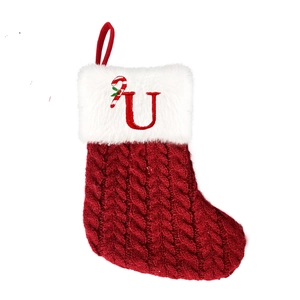 Close-up of red cable knit Christmas stocking with white fur trim and letter U embroidery