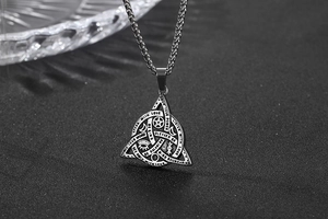 Macro shot of silver triangle pendant featuring mystical symbols and engraved quotes