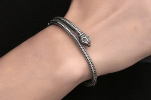 Gros plan du bracelet serpent argenté avec écailles en relief et yeux en strass rouges
