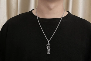 Détail du pendentif Faucheuse vintage sur une chaîne Franco en acier inoxydable