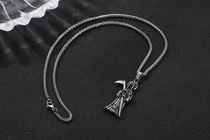 Detailed view of vintage grim reaper pendant with scythe on textured black background