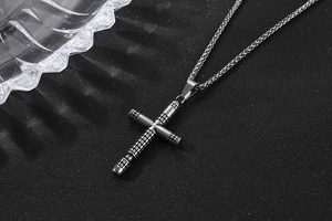 Close-up of vintage steel cross pendant with anti-slip grid texture on black background