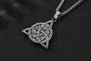 Macro shot of a triangular stainless steel pendant with mystical engravings and box chain